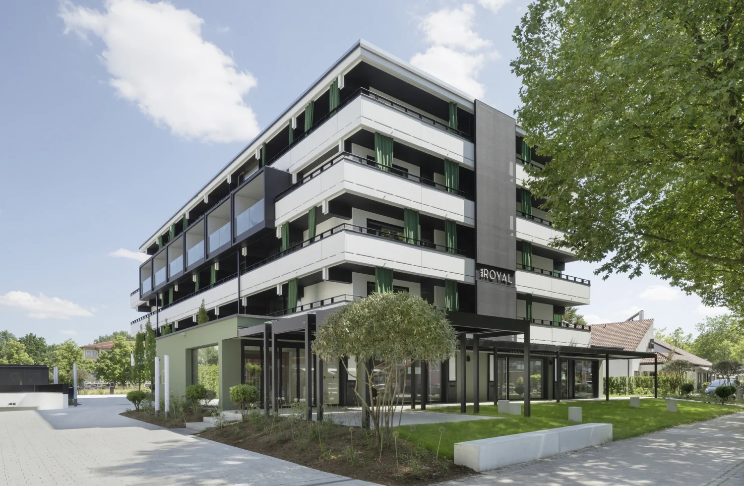 Modernes Hotelgebäude mit grünen Balkonen und blauem Himmel